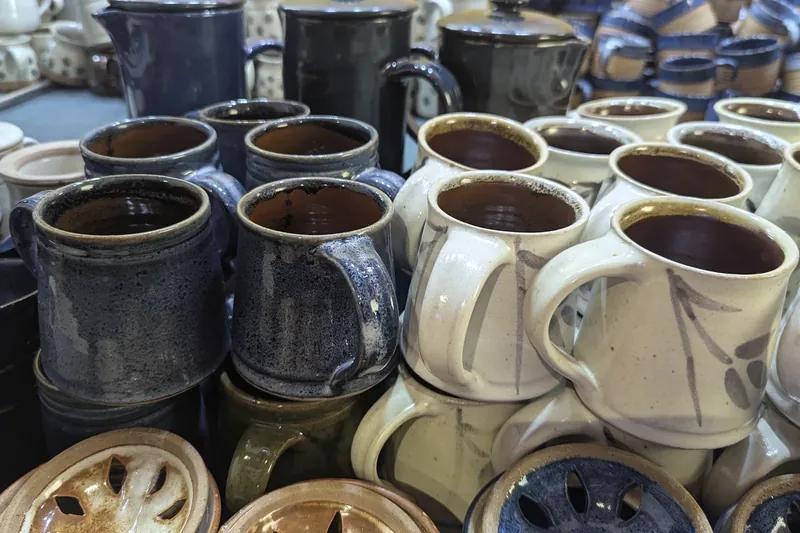 Close-up of stacked stoneware mugs in cream and deep blue glazes.