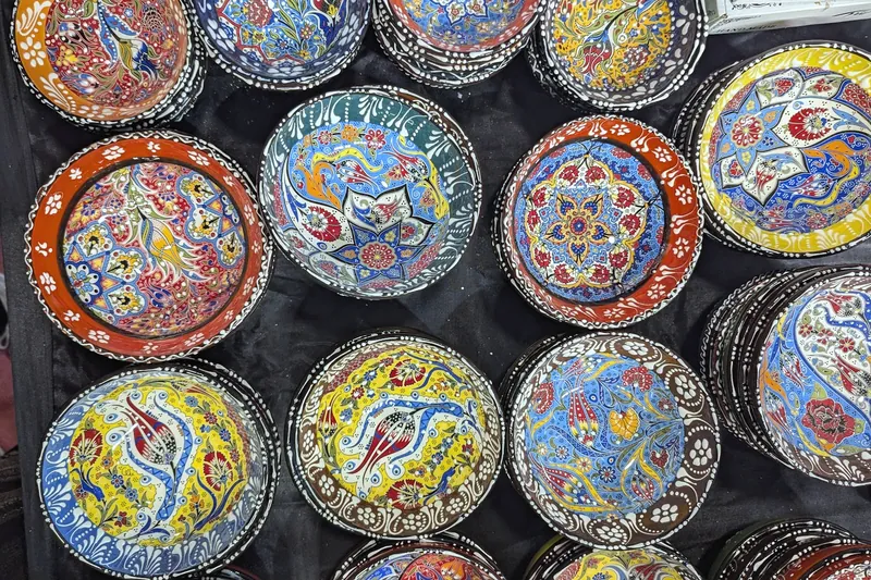 Top-down view of colourful hand-painted ceramic bowls with floral and tulip motifs.