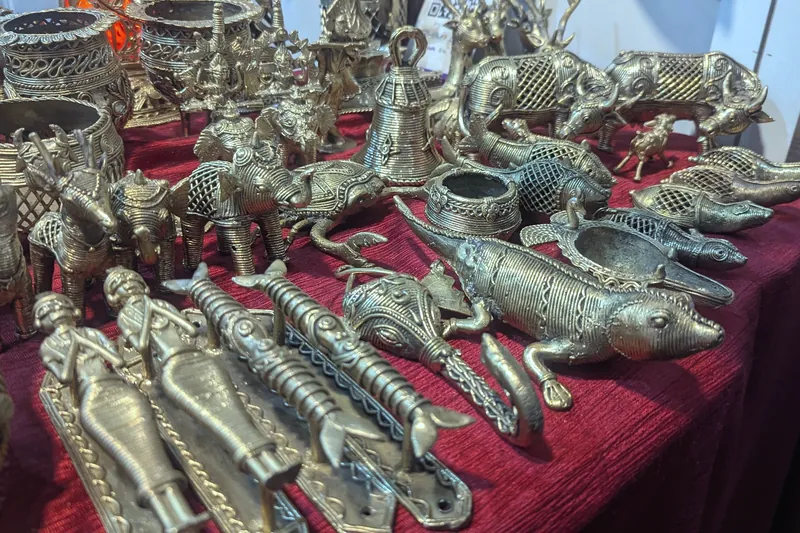 Rows of lost-wax cast brass animals and figures on a red cloth.
