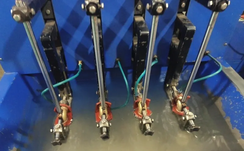 Four brass valves clamped in a blue test rig, submerged in a water tank and fed by air lines.