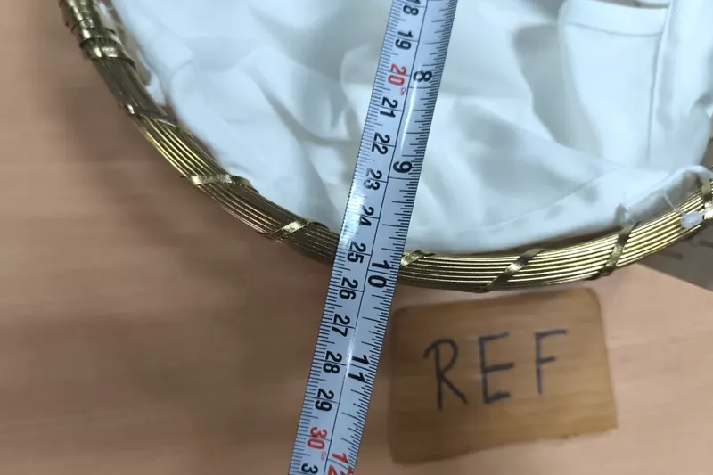 A tape measure laid across a gold wire basket lined with white fabric.