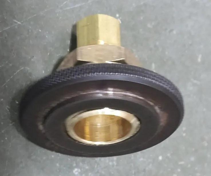 A knurled black thread gauge screwed onto a brass fitting on a concrete bench.
