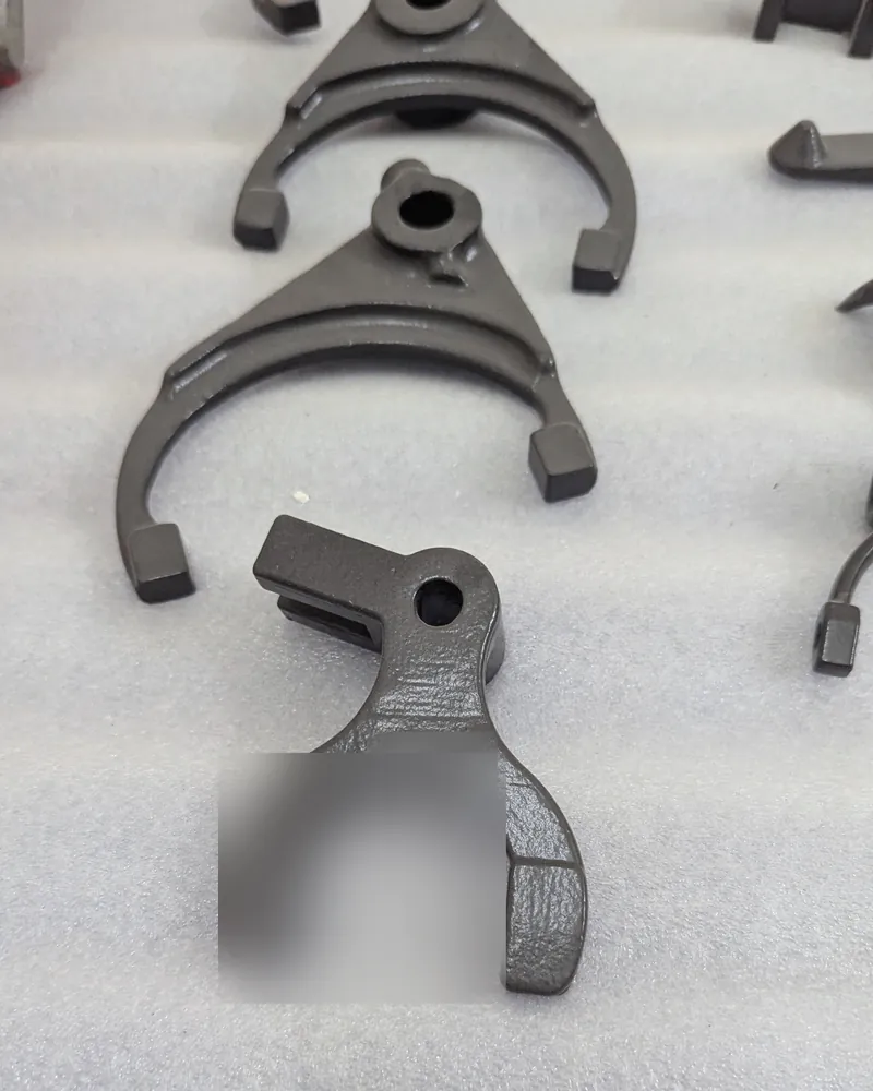 Dark grey cast shift forks and levers laid out on a white foam sheet.